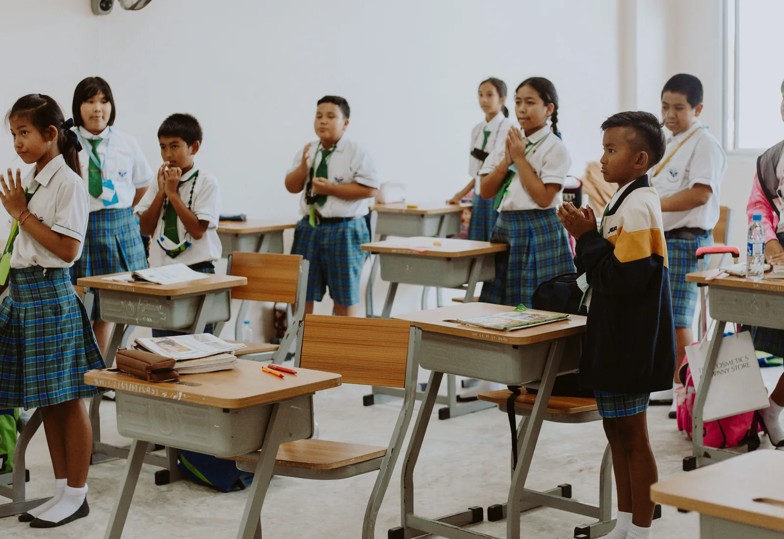 Uniformed school students standing beside classroom desks during a lesson